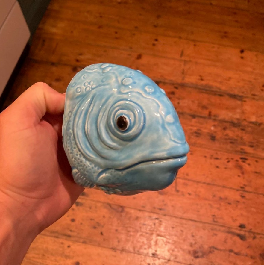 Handmade ceramic Fish wall sculpture held in a hand, showing its aquamarine glaze.