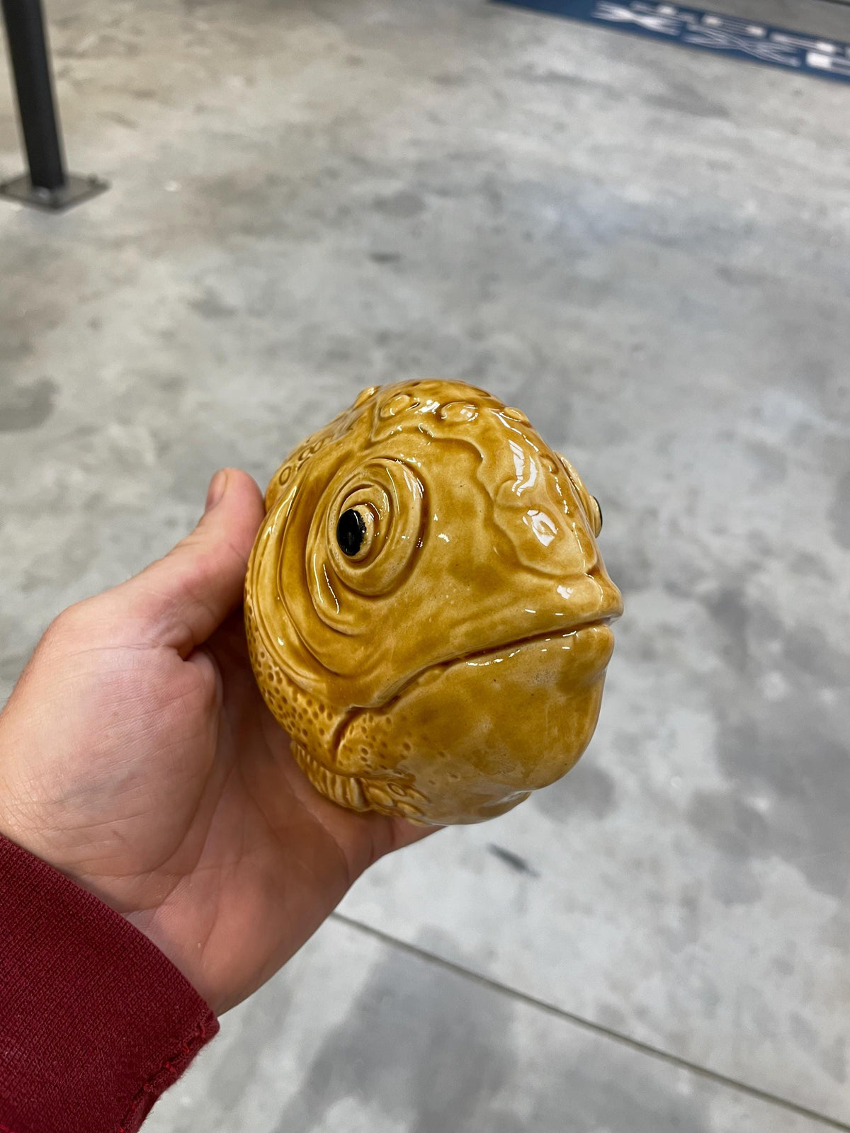 Handmade ceramic Fish wall sculpture held in a hand, showing its cognac glaze.